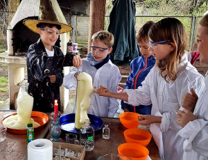 Kinder in Laborkitteln experimentieren mit schäumender Flüssigkeit