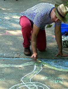Spielleiter Robert Mingau malt mit Kreide eine Auto-Rennstrecke auf das Pflaster