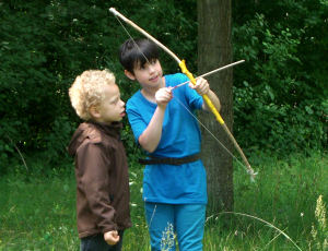 Zwei Kinder beim Bogenschießen im Wald