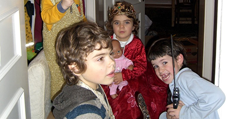 Fröhliche Kinder, darunter ein Mädchen im Prinzessinnen-Kostüm, bei einem Kindergeburtstag in einer Wohnung