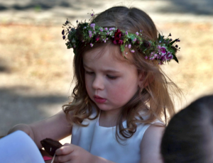 ein kleines Mädchen mit Blumenkranz im Haar ist in eine Bastelarbeit vertieft