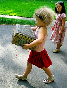 ein kleines Mädchen trägt stolz eine große Schatztruhe