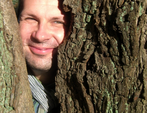 Portrait Robert Mingau, durch einen Baum blickend